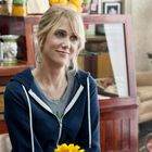 Ich kann die Person nicht erkennen, aber sie lächelt freundlich in einem gemütlichen Café, vorne ein gelbe Blume.