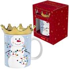 „Tasse mit Kronendeckel“. Schneemann-Motiv, umhüllt von Lichterkette, goldener Kronendeckel, rote Verpackung.