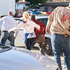 "To protect and to serve" auf einem Polizeiauto. Ein Polizist zielt mit einer Waffe auf blutige Menschen. Chaos auf der Straße.