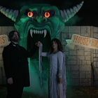 Texte: "Dr. Mortis' House of Horrors". Ein Paar vor großem Monsterkopf mit leuchtenden Augen und großen Hörnern.