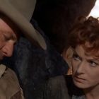 Ich kann den Text nicht erkennen. Zu sehen ist ein Mann mit Cowboyhut und eine Frau in angespannter Situation.