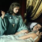 Keine Texte vorhanden. Eine Frau in einem grünen Gewand hält ein Messer. Sie steht neben einem schlafenden Paar im Bett.