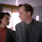 Zwei Personen in einem Anzug führen ein intensives Gespräch in einem modernen Raum mit weichen Lichtquellen.