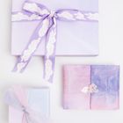 Drei Geschenke mit pastellfarbenem Papier, eine Schleife mit Wolkenmuster, zartes Lila und Rosa.