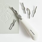 Text: "RICO DESIGN". 

Eine Linolschnitt-Werkzeug mit mehreren Aufsätzen und Blattmuster auf hellem Papier.