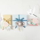 „Für Mama“ ist auf einem Taubenanhänger zu lesen. Bunte Geschenke mit Blumen-Dekoration sind arrangiert.