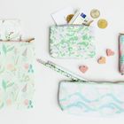 "RICO DESIGN" auf mehreren pastellfarbenen Täschchen mit floralen und geometrischen Mustern, Münzen und Herzen.