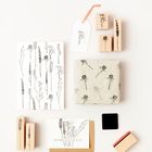 "Ein Dankeschön für alles" auf einer Karte, umgeben von Stempeln und Papier mit botanischen Motiven.