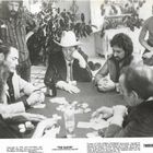 "The Glove" steht im unteren Bereich. Mehrere Männer sitzen an einem Tisch beim Kartenspiel.