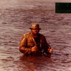 Text: "CUL ET CHEMISE" oben rechts. Ein Mann steht bis zur Taille im Wasser, trägt Hut und Jacke, hält ein Steuer.