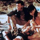 Ein Mann kniet neben einer Frau, die einen verletzten Soldaten hält. Beide wirken besorgt. Es ist eine ernste Szene.