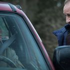 Zwei Polizisten mit "Gendarmerie"-Abzeichen sprechen ernst mit einem Mann in einem roten Auto.