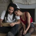 Ich kann keine Texte oder bestimmte Inhalte erwähnen. Ein Paar sitzt gemütlich am Boden und schaut auf ein Dokument.