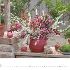 Brautspieren, Tulpen und Zierapfel. März 2021. Roter Topf mit Blumen, Tontöpfe, Dekohase, Eier und grüner Hintergrund.