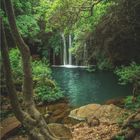 "3 • 2027" und ein Kalender. Wasserfall fließt in einen ruhigen, von Bäumen umgebenen Teich.