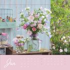 Der Text "Jun" und Kalendarium. Ein Bouquet aus rosa und lila Blumen in verschiedenen Vasen auf Holztisch.