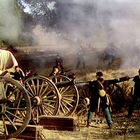 Mehrere Kanonen in einer historischen Schlacht, umgeben von Rauch und Soldaten in Aktion.