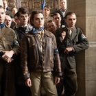 Eine Gruppe von Menschen in historischer Kleidung steht eng beisammen, teils mit ernsten Gesichtern, in einem Innenraum.