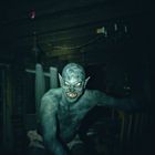 Ein unheimliches Wesen mit spitzen Ohren und leuchtenden Augen in einem dunklen Raum mit Holzdecke und Möbeln im Hintergrund.