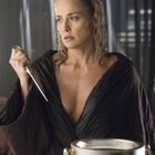 Eine Frau mit nassen Haaren hält einen Dolch und trägt einen dunklen Umhang. Vor ihr steht ein Eiskübel.