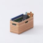 Holzkiste mit Büchern, Brille, Lineal, Lederetui und Notizbuch, auf hellem Hintergrund.