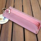 Runder Papieranhänger mit "Emily Flat Pencase". Rosa Mäppchen mit Reißverschluss und Metallring auf Holztisch.