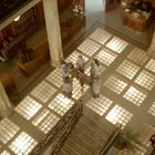 Eine Gruppe Frauen steht auf einem marmorboden in einer historischen Halle mit Treppe und hohen Säulen.