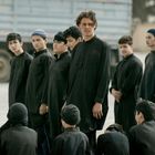 Eine Gruppe von Teenagern in schwarzer Kleidung steht draußen, einige sitzen. Im Hintergrund ein Lastwagen.