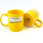 Auf zwei gelben Tassen steht: "Universal-Tasse" und "Reclam". Eine Tasse liegt, die andere steht.