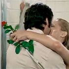 Ein Paar umarmt sich unter der Dusche und küsst sich. Der Mann hält eine rote Rose.