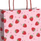 Keine Texte. Eine Geschenkpapier-Tasche mit Erdbeermuster, roten Herzen und kleinen Blumen auf rosa Hintergrund.