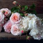 Ein Strauß aus rosafarbenen und weißen Rosen mit grünen Blättern auf einem Tisch.