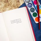 Eine Buchseite mit folgendem Text: "To you, reader, wherever you are, may this life be kind to you, and may you always remember to be kind to yourself." Daneben befinden sich Aquarellfarben und ein Pinsel.
