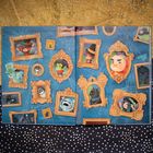 Eine Wand mit Bilderrahmen, gefüllt mit Karikaturen von Hexen, Monstern und Tieren auf blauem Hintergrund mit Spinnweben.