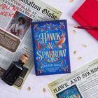 Der Titel "Hawk & Sparrow" in Gold auf blauem Buch. Daneben Zeitungsartikel, angestrichen mit "YOU'RE NEXT" in Rot.