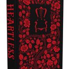 „HEARTLESS“ in roter Schrift auf schwarzem Hintergrund, umgeben von roten Blumen und Blättern als dekoratives Muster.