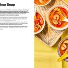 Titel: Hot and Sour Soup; Zutaten: Öl, Zwiebel, Pilze, Hühnerbrust, Garnelen, MSG, Wasser, Tom-Yum-Paste, Zucker, Tomaten, Sojasprossen. Links Text, rechts Suppenschalen auf gelbem Tuch.