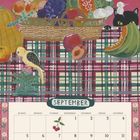 SEPTEMBER in Großbuchstaben. Ein kunstvolles Stillleben mit Früchten, einem Vogel und einer schwarzen Katze auf karierter Decke.