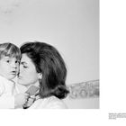 Text: "Opposite: JFK Jr. didn't inherit his father's..."

Eine Frau hält ein Kind. Die Frau hat volles Haar, das Kind hält etwas in der Hand.