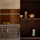 Text: Beschreibung eines unauffälligen Gebäudes von Pau Munar. Küche mit Holzwänden, Obst auf Theke, Regale mit Keramik.