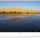 "Der Nil im Morgenlicht". Eine Flusslandschaft mit sanften Hügeln, blauem Himmel und ruhigem Wasser.