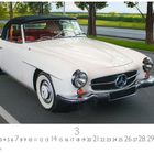 Mercedes 190 SL, März, Casares Edition. Ein weißer Oldtimer-Cabriolet auf einer Straße, von Bäumen flankiert.