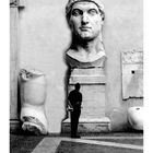 "Kapitolinische Museen." Ein Mann betrachtet eine riesige antike Statue, deren Kopf und Gliedmaßen an einer Wand angeordnet sind.