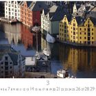 Ålesund. Eine Reihe bunter Gebäude spiegelt sich im Wasser eines Hafens, mit mehreren ankernden Booten.