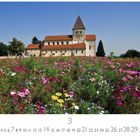Kalenderblatt für März, darunter ein Blumenfeld vor einem historischen Gebäude mit rotem Dach und Turm.