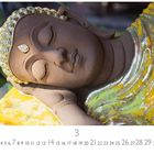 Zahl 3 und Datumsreihe 1-31; rechteckige Buddha-Skulptur aus Ton, ruht in entspannter Pose, trägt goldene Verzierungen.