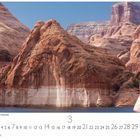 "Bergkette am Lake Powell Stausee." Sandige Felsen erheben sich über einem ruhigen blauen See.