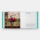 Text "Foreword" auf einer Buchseite. Links ein Tisch mit Kerzenständern und einem Blumenarrangement in Rot.