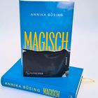 Buchcover: "Annika Büsing, MAGISCH". Darunter: "S. Fischer". Blau-gelbes Design, zwei Bücher übereinander.
