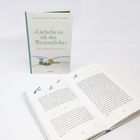 Buchcover mit "Lächeln ist oft das Wesentliche". Geöffnetes Buch zeigt Text und kleine Zeichnungen von Vögeln und Sternen.
